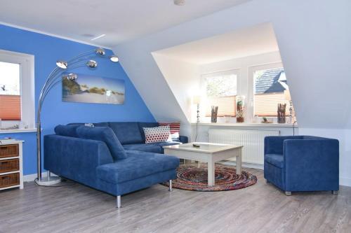 sala de estar con sofá azul y mesa en Amselweg 5, en Süderende