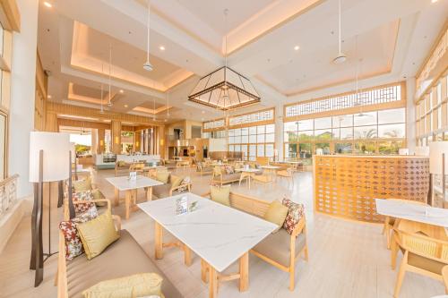a restaurant with tables and chairs and windows at Glenmarie Hotel and Golf Resort in Shah Alam