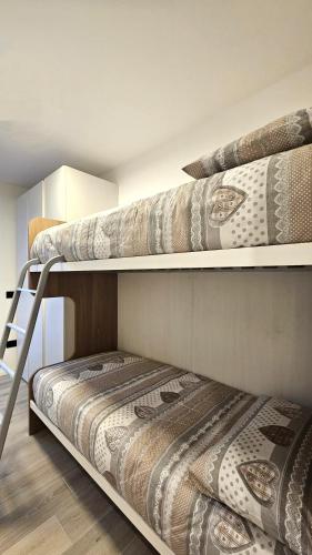 two bunk beds in a room with a bed at ANDALO RELAX APARTMENT in Andalo