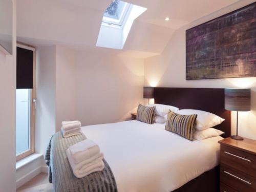 Un dormitorio con una cama blanca con toallas. en Your Space Apartments - Cambridge Place, en Cambridge