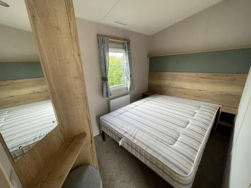 a small bedroom with a bed and a window at Dainville Caravan Park in Skegness