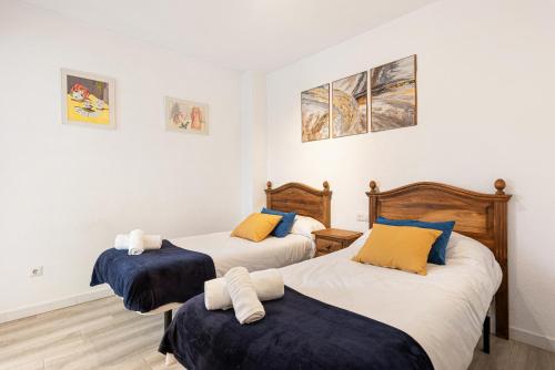 a bedroom with two beds with blue and yellow pillows at Casa Cañi in Málaga