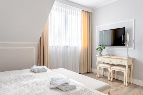 biała sypialnia z łóżkiem i biurkiem z telewizorem w obiekcie Filip Pokoje - Osłonino nad zatoką w mieście Osłonino