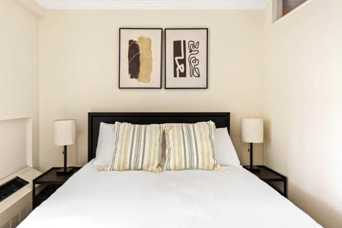 1 dormitorio con 1 cama blanca y 2 lámparas en Nolita 2BR w Elevator Roof nr Little Italy NYC-921, en Nueva York