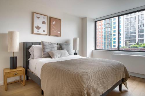 - une chambre avec un grand lit et une grande fenêtre dans l'établissement Upper West Side 1br w doorman nr park NYC-1219, à New York