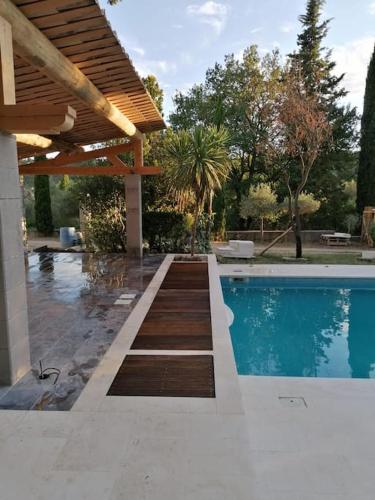 - une piscine dans un jardin avec une pergola en bois dans l'établissement Un écrin à Cornillon en Provence, à Cornillon-Confoux