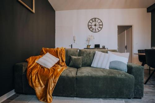 a living room with a green couch with a blanket at Le Bertrand • Le Raffinement en Cœur de Ville in Châteauroux