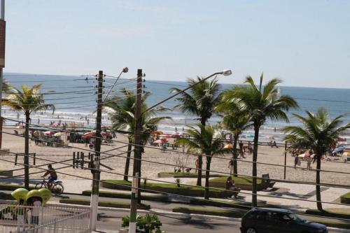 een uitzicht op een strand met palmbomen en de oceaan bij Apartamento Praia Grande Frente Mar in Praia Grande