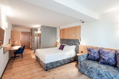 Habitación de hotel con cama y sofá en Hotel Nele, en Ziano di Fiemme