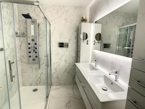 une salle de bain blanche avec une douche et un lavabo dans l'établissement Appartements centre ville Cannes, à Cannes