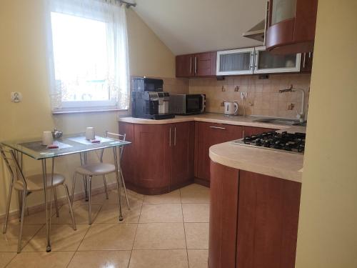 eine Küche mit Holzschränken und einem Tisch mit Stühlen in der Unterkunft Apartament 'Siwy Dom' 