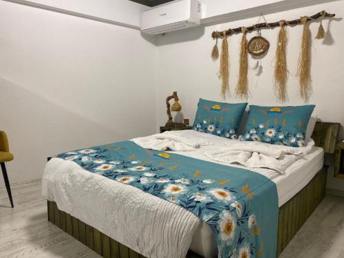 a bed with a blue comforter with flowers on it at Scala Otel in Cesme