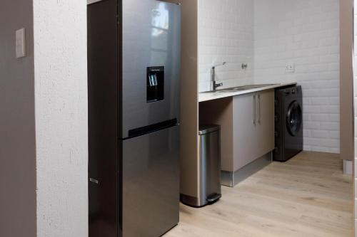a stainless steel refrigerator in a kitchen with a sink at Uptown Luxury Villas in Nelspruit