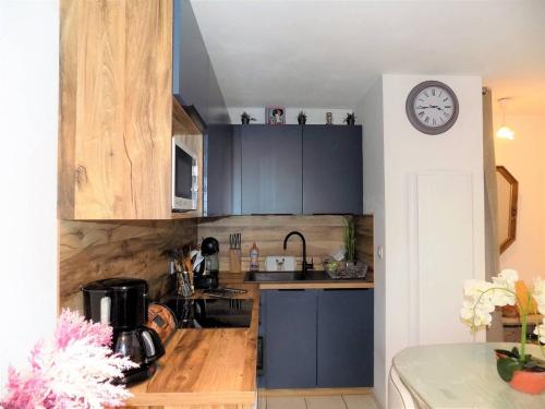 une cuisine avec des placards bleus et une horloge murale dans l'établissement Royan - APPARTEMENT au COEUR du CENTRE-VILLE - PLAGE à SEULEMENT 200m, à Royan