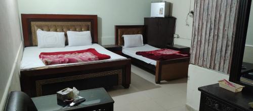 ein Hotelzimmer mit 2 Betten und einem Tisch in der Unterkunft Hotel New Star in Multan
