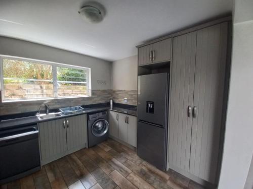 een keuken met een wasmachine, een wastafel en een vaatwasser bij 22 Oaklands on the Knoll in Knysna