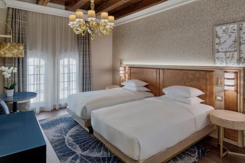 two beds in a hotel room with a chandelier at Hilton Molino Stucky Venice in Venice