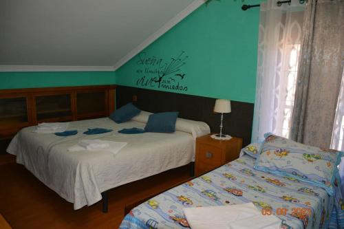1 dormitorio con 2 camas y pared azul en Cómoda casa en Cabárceno, en Villanueva