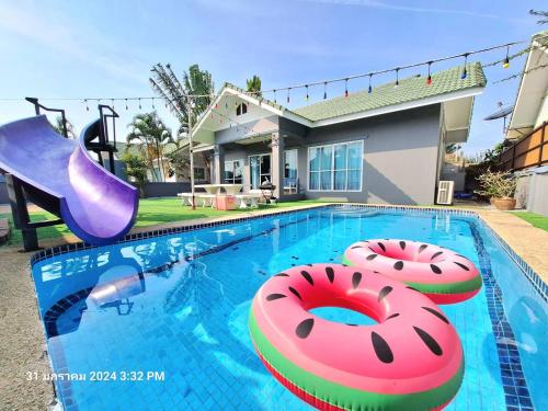 a swimming pool with two inflatables in front of a house at มัลดีฟส์ เวนิซ ไมอามี่ กรีนที หัวหินพูลวิลล่า Maldive Venice Miami Green Tea Hua-Hin Pool Villa in Hua Hin