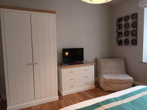 a bedroom with a tv and a cabinet and a chair at L'ALBIZIA in Libin