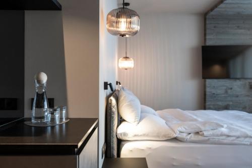 a bedroom with a bed and a table and lights at Hotel Viertler in Avelengo