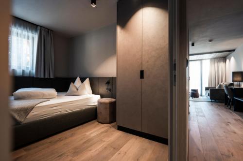a bedroom with a bed and a living room at Hotel Viertler in Avelengo