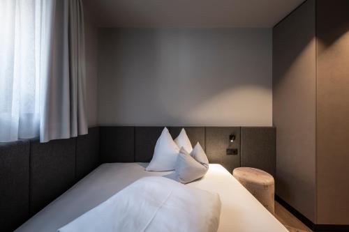 a bedroom with a bed with white sheets and pillows at Hotel Viertler in Avelengo