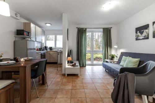 ein Wohnzimmer mit einem blauen Sofa und einer Küche in der Unterkunft Arkadia Haus Alstertal in Hamburg