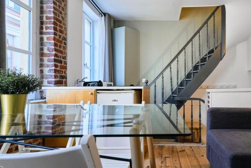 une salle à manger avec une table en verre et des escaliers dans l'établissement Grand-place & Vieux-Lille: Equipped duplex, à Lille