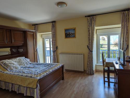 een slaapkamer met een bed, een bureau en ramen bij Chambres d'Hôtes La Terrasse d'Argein in Argein