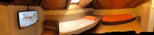 a small room with two beds and a flat screen tv at Garni Villa Betty in Merano