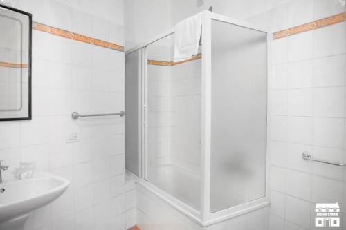 uma casa de banho branca com um chuveiro e um lavatório. em TORRETTA 4 by Design Studio em Bellano
