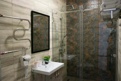 a bathroom with a sink and a shower with a mirror at Tengri Hotel in Aktau