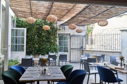 een restaurant met tafels en stoelen en een heg bij Logis Hôtel de la Tour in Libourne