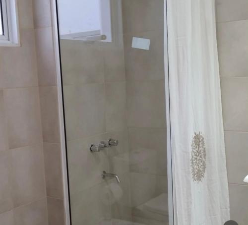 a shower with a glass door with a shower curtain at Apart Hotel Concepcion in Concepción