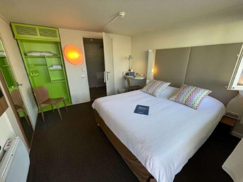 a bedroom with a large bed with a book on it at Campanile Annecy - Cran Gevrier in Annecy