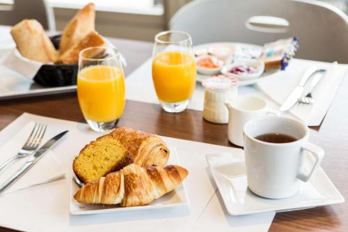 - une table avec une assiette de pain et de jus d'orange dans l'établissement Campanile Annecy - Cran Gevrier, à Annecy