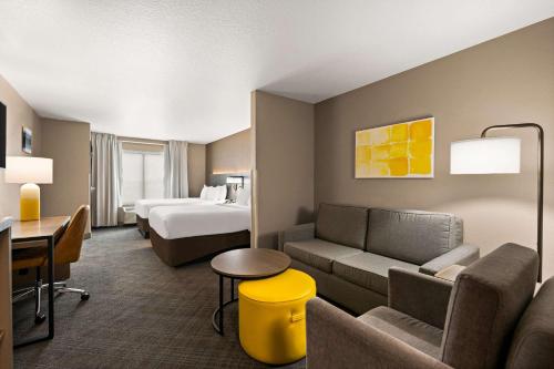 Comfort Suites Hudson I-94 في هدسون: غرفه فندقيه بسرير واريكه