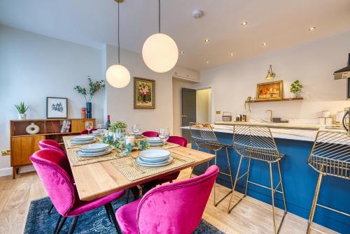 a kitchen and dining room with a wooden table and pink chairs at Haworth Heights - An AMAZING Aparthotel! in Haworth