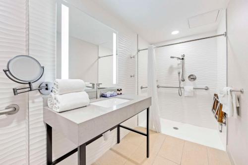 a white bathroom with a sink and a shower at The Capitol Hotel Downtown, Ascend Hotel Collection in Nashville