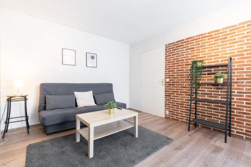 - un salon avec un canapé et un mur en briques dans l'établissement Fully-equipped apartment near the center of Lille, à Lille