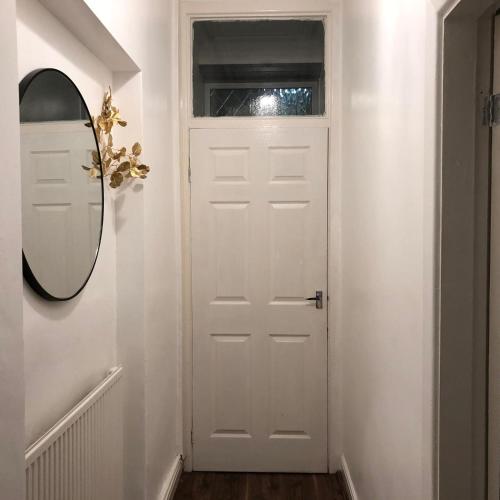 a hallway with a white door and a mirror at Comfortable Home From Home Bolton Central - Sleeps - 10 in Bolton