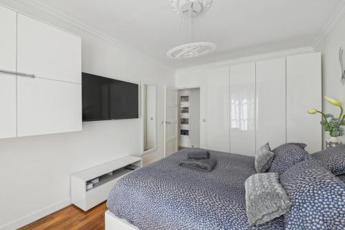 a white bedroom with a bed and a flat screen tv at Élégance parisienne près des Champs-Élysées in Paris