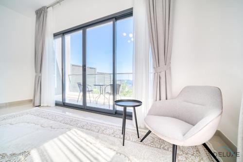 a white chair in a room with a large window at Best Deal, Classy 4BR Villa with Pool & Ocean Views by Deluxe Holiday Homes in Fujairah