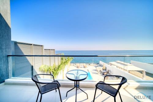 a balcony with three chairs and a table and the ocean at Best Deal, Classy 4BR Villa with Pool & Ocean Views by Deluxe Holiday Homes in Fujairah