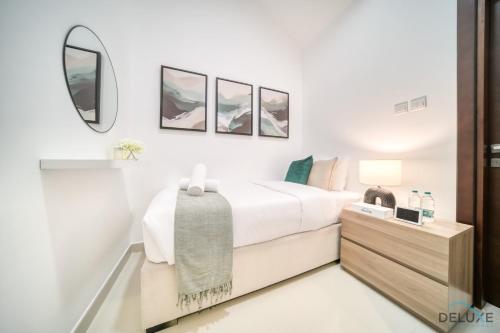 a white bedroom with a bed and a mirror at Best Deal, Classy 4BR Villa with Pool & Ocean Views by Deluxe Holiday Homes in Fujairah