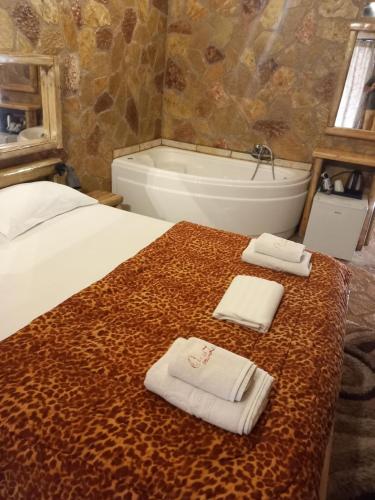 - une chambre avec un lit et une baignoire avec des serviettes dans l'établissement Ζachlorou Mood, à Kalavrita