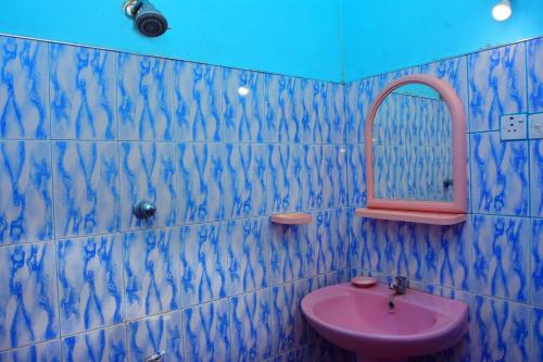 La salle de bains est pourvue d'un lavabo rose et d'un miroir. dans l'établissement Randeniya Rest inn, à Wellawaya