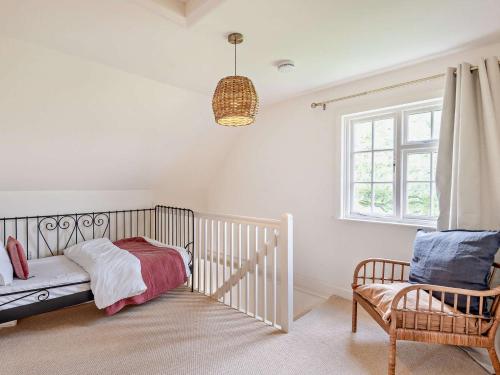 斯托克羅奇福德的住宿－2 Bed in Stoke Rochford 93039，一间卧室配有婴儿床、椅子和窗户。
