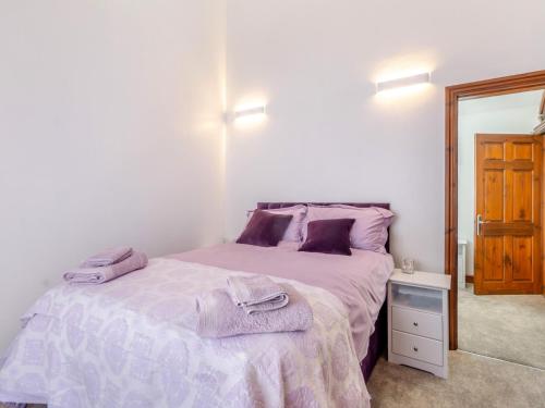a bedroom with a bed with purple sheets and a mirror at 2 Bed in Saxilby 93058 in Saxilby
